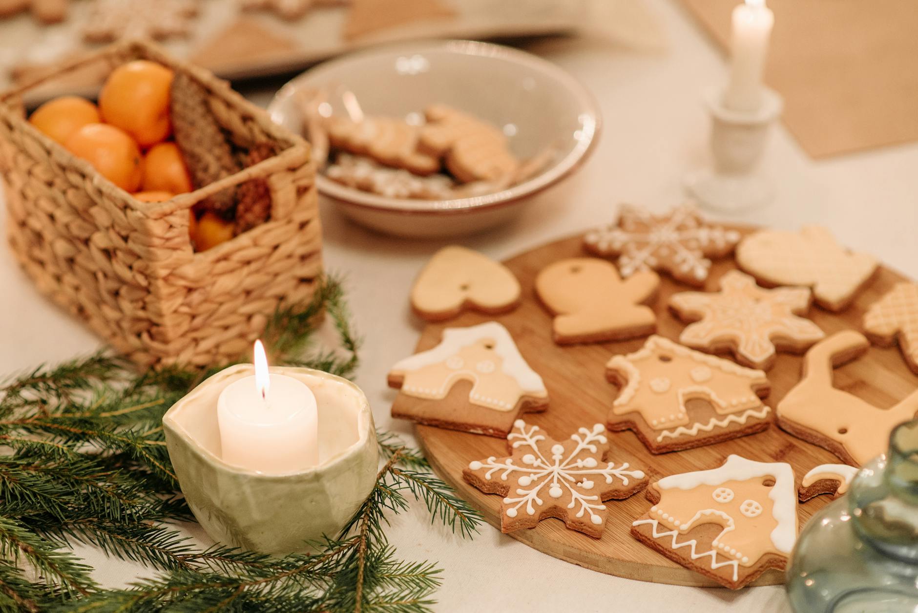 Warm holiday scene with gingerbread cookies, candles, and tangerines on a festive table.