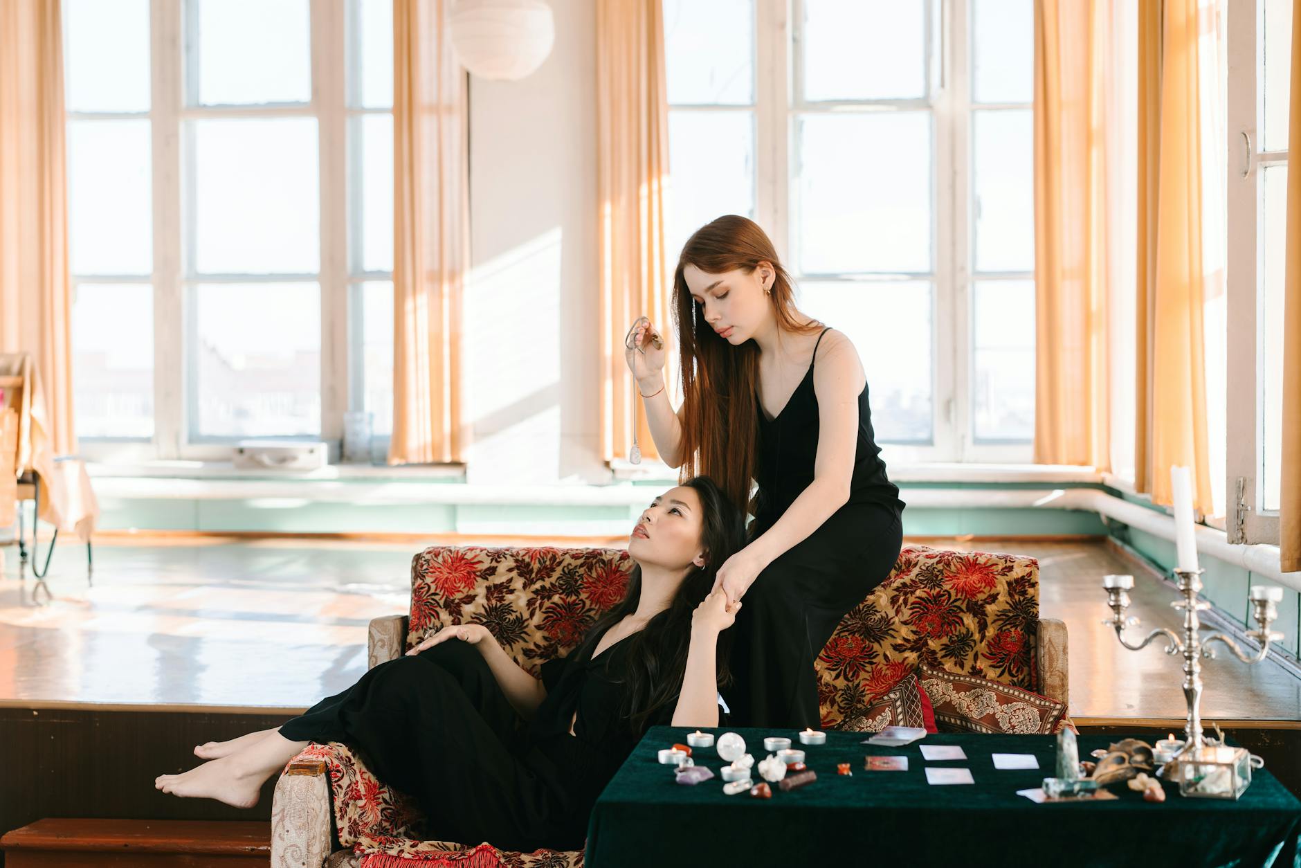 Two women in a peaceful indoor setting, engaged in meditation with crystals and tarot cards.
