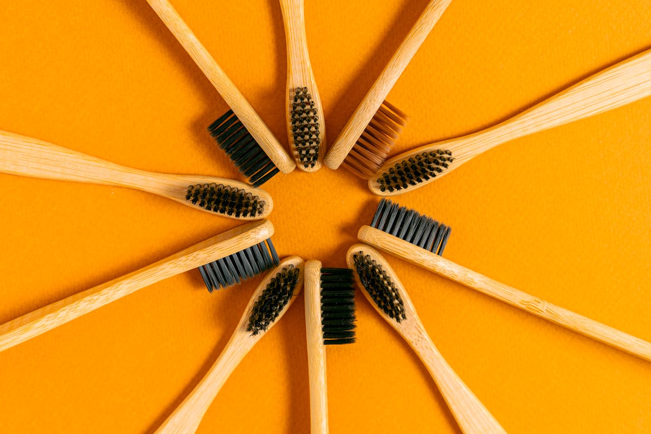 Circular arrangement of bamboo toothbrushes on a vibrant orange surface showcasing eco-friendly dental care.