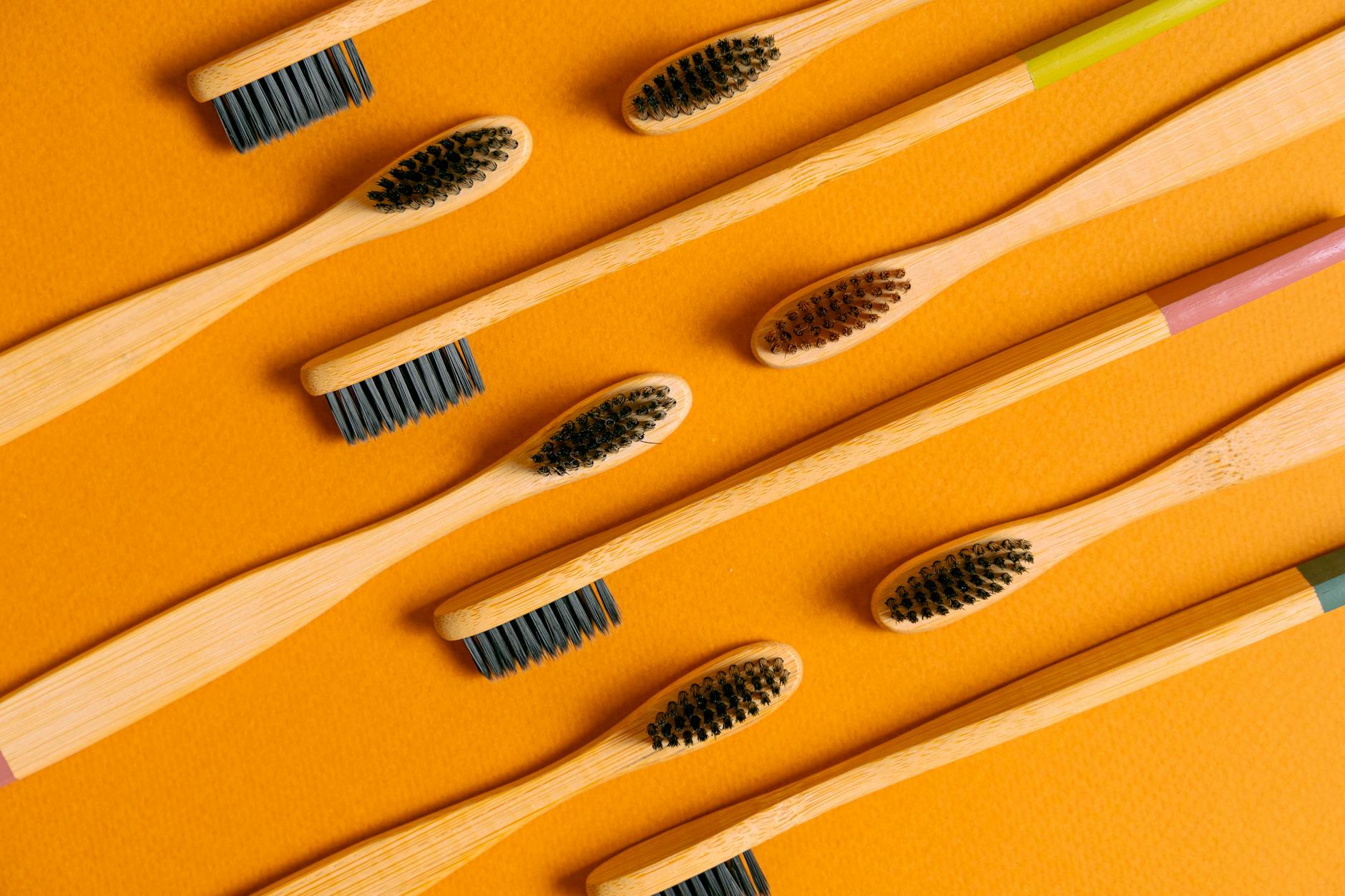 Close-up of bamboo toothbrushes on an orange background, emphasizing eco-friendly oral care.