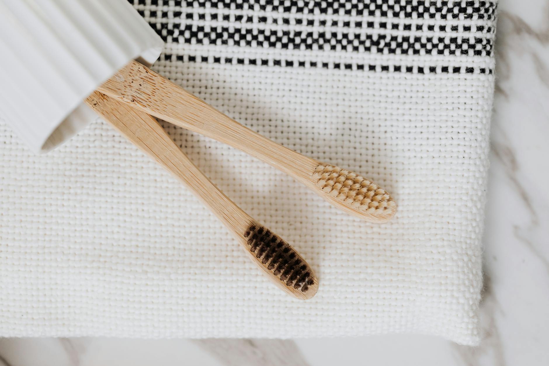 Aesthetic close-up of wooden toothbrushes on a stylish white textile surface, promoting eco-friendly hygiene.